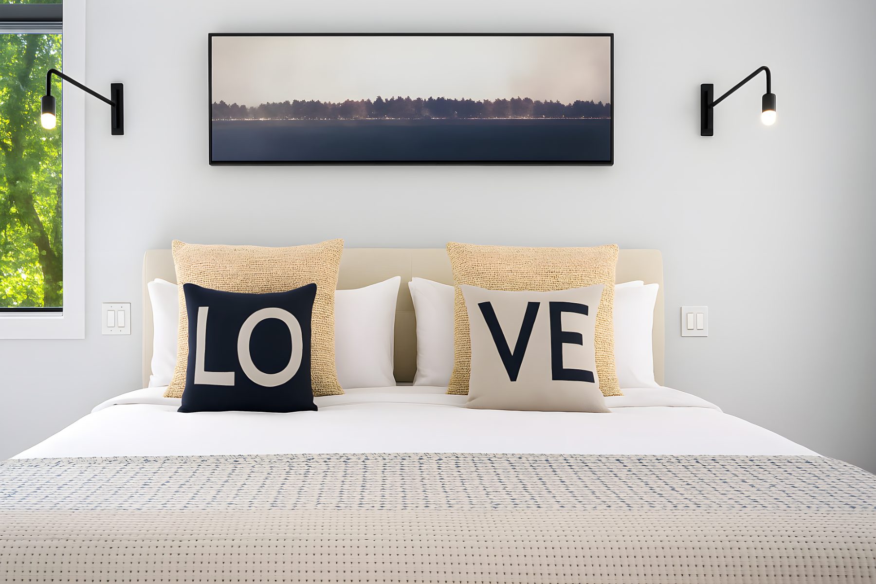 Bed with LOVE pillows beneath a long horizon photograph